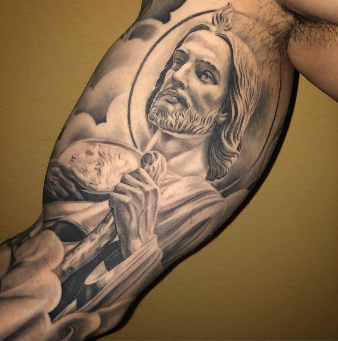 Tatuaje de San Judas en el bíceps.
