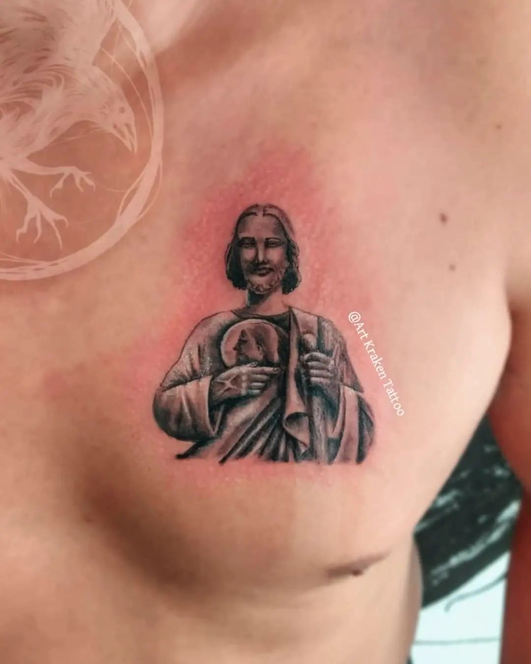 Tatuaje pequeño de San Judas en el pecho.