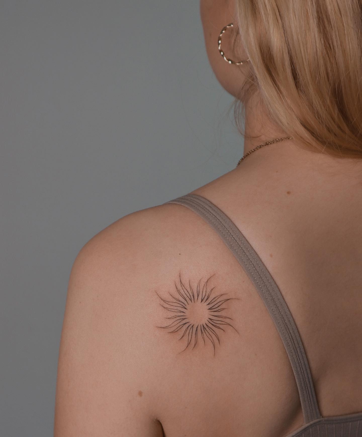 Tatuaje pequeño de sol en el hombro.